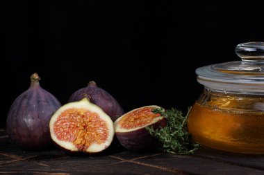 İncir bütün mor ve koyu bir arka plan bir kavanoz ıhlamur bal yanında kesmek.