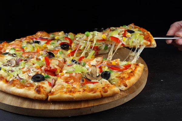 Bunlardan biri bir spatula ile çekilir parçalar halinde kesilmiş vejetaryen çok renkli pizza,.