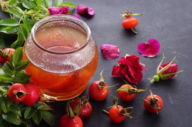 Yabani gül reçeli, çilek ve bitkinin tomurcukları yakınındaki bir kavanoz.