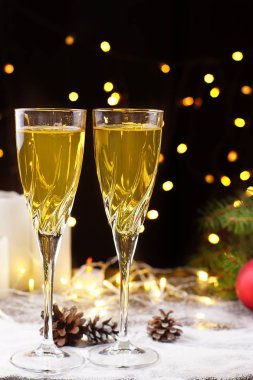 İki kadeh şampanya ya da masada, suyu ile süslenmiş parlayan çelenk, Noel ağacı dal ve beyaz mumlar