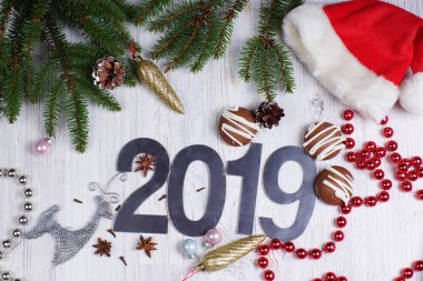 Rakamlar 2019, kurabiye ve Noel süslemeleri ile hafif bir arka plan üzerinde kırmızı bere ile bir Noel ağacı. Yeni yıl kavramı. Tebrik Noel kartı. Düz yatıyordu.