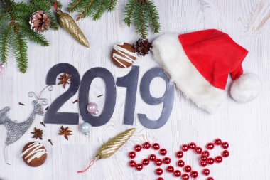 Noel düzen sayı 2019, Santa şapka, çam dalları ve süslemeleri üzerinde hafif bir arka plan ile. Yeni yıl kavramı. Tebrik Noel kartı. Düz yatıyordu.
