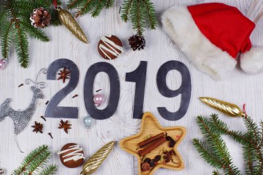 Noel düzen sayı 2019, Noel Baba şapkası, süslemeleri ve Noel ağacı dalları hafif ahşap zemin ile... Yeni yıl kavramı. Tebrik Noel kartı. Düz yatıyordu.