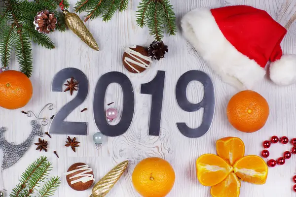 Numaraları 2019, Santa şapka, süslemeleri ve Noel ağaç dalları ve hafif bir arka plan üzerine mandalina ile Noel düzeni. Yeni yıl kavramı. Tebrik Noel kartı. Düz yatıyordu.