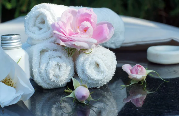 Set for outdoor spa treatments, folded white towels, soap, lotion and fragrant flowers — Stock Photo, Image