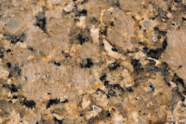 Koyu sıçramaları ve çatlakları ile doğal taş sarı-kahverengi granit