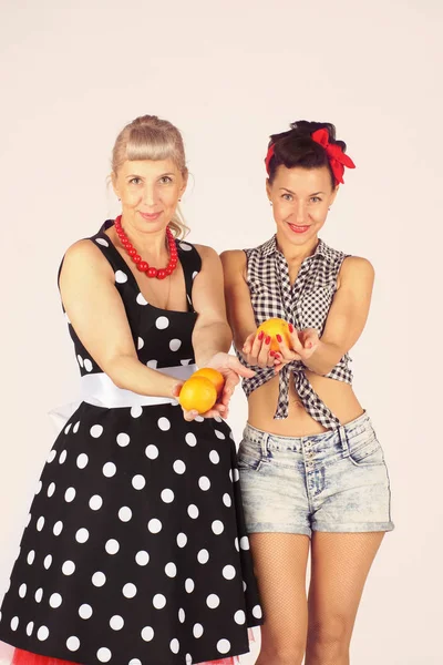 İki pinup kız ellerinde portakal tutuyor, onlara teklif