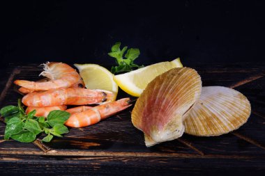 Karidesler ve kabuklarda taraklar pişirmeden önce diğer malzemelerin yanında yatıyor.