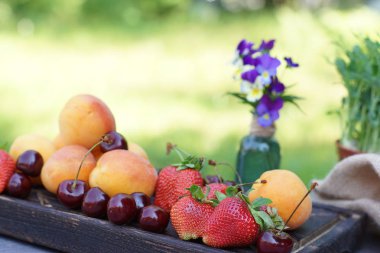 Meyve ve çilek doğada bir masa üzerinde ahşap bir tahta üzerinde, bir kavanozda bir buket yanında yalan