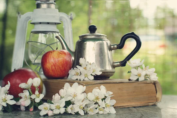 Bodegón con manzanas, una tetera y delicadas flores sobre la mesa — Foto de Stock