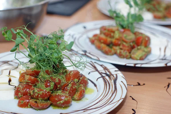 En la cocina, una ensalada caprese recién preparada con pesto y tomates cherry para varias personas —  Fotos de Stock