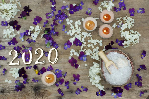 Figuras 2020 sobre un fondo de madera junto a las flores de marrones morados y sal de baño blanca, concepto de spa — Foto de Stock