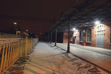 Demiryolu platformu kırmızı tuğla istasyonun yanındaki karla kaplı, eski bina..