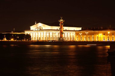 Rusya 'daki St. Petersburg şehrinin simgeleri, Neva Nehri' nin diğer tarafındaki demiryolu sütunlarının gece aydınlanmasıyla....