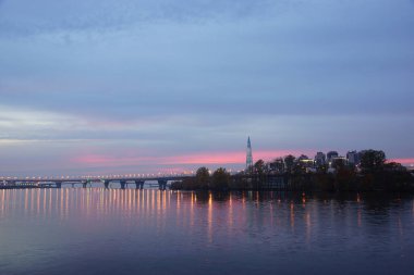 Finlandiya Körfezi 'ndeki güzel günbatımı binaları suyun pürüzsüz yüzeyine ve gökyüzündeki kırmızı bulutlara yansımaktadır.