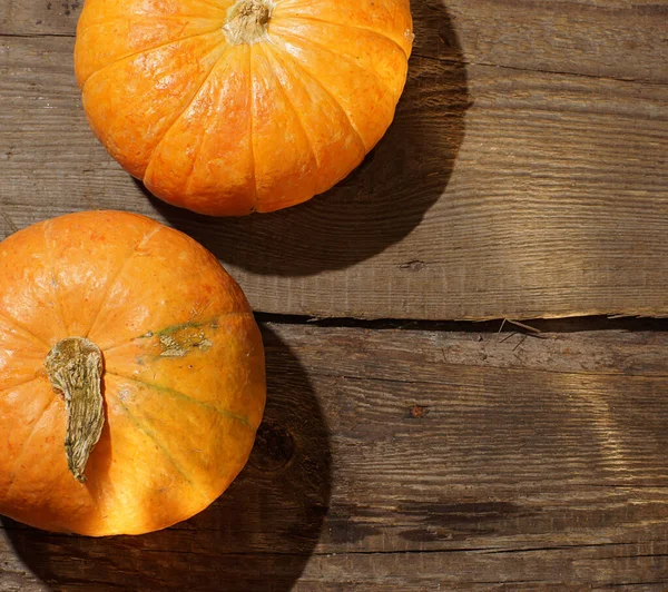 Tahta bir masada iki balkabağı yatıyor..
