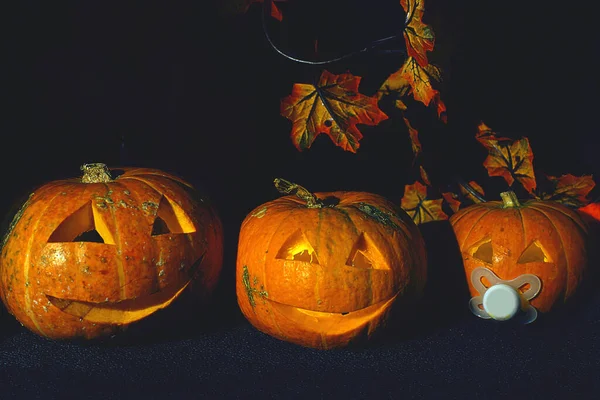 Tre Pumpor Med Ansikten Och Ljus Inuti Mörk Bakgrund — Stockfoto