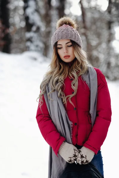 美丽时尚的女孩享受美妙的冬季降雪在森林公园站在外面 并举行包手套戴针织帽子呼呼球 灰色围巾和红色夹克雪的天气雪花飞行雪花美丽时尚休闲服女人好 Moo — 图库照片