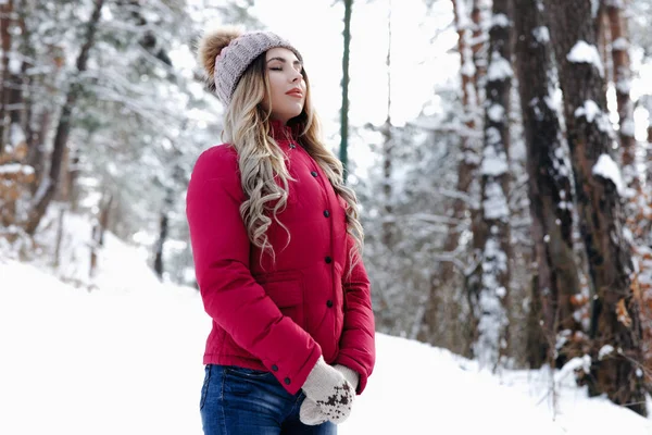 漂亮的女人在红色羽绒服 蓝色牛仔裤和针织帽子和手套呼吸自由空气弗隆冬季森林 闭着眼睛 寒假概念 — 图库照片