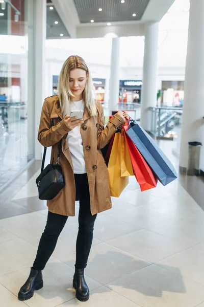 Young Blonde Girl Types Something Her Phone Staying Mall Shopping — Stock Photo, Image