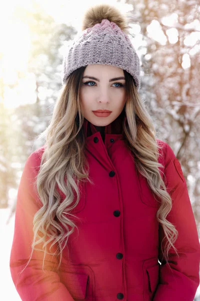美丽的女人与蓝眼睛和金色的郁郁葱葱的头发穿着针织帽子和红色羽绒服的时尚肖像 寒假概念 — 图库照片