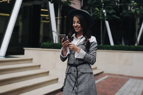 Buiten portret van knappe lachende vrouw met mobiele telefoon in — Stockfoto