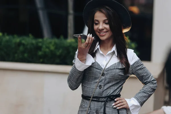 Vrouw staande op straat houdt telefoongesprekken op speakerphone of m — Stockfoto