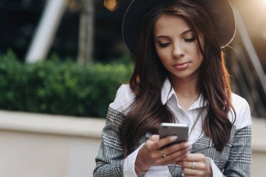 Cep telefonu oyunları oynarken akıllı telefon kullanarak modern siyah şapka ile iyi görünümlü kadının portresi kadar yakın