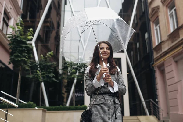 Portret van een gelukkige vrouw onder een paraplu in de buurt van het kantoor. Cop — Stockfoto