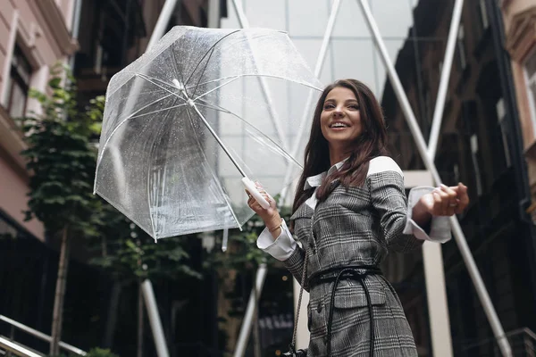 Retrato de una mujer feliz riéndose bajo un paraguas cerca de la vieja casa, esperando la lluvia. Es lluvia primaveral . —  Fotos de Stock