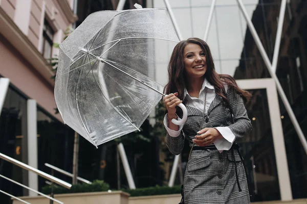 Retrato de una mujer feliz riéndose bajo un paraguas cerca de la oficina. Copia el espacio en el lado izquierdo. Es lluvia primaveral . — Foto de Stock