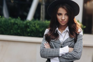 Siyah şapka lı ve gri palto giyen güzel kadının portresi, çapraz kollar. Model kenara bakıyor.