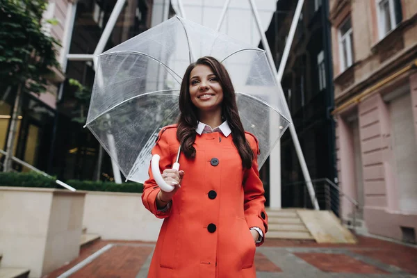 Beautiful woman with umbrella rainy day in red coat standing nea — Stock Photo, Image