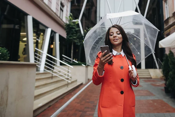 Mooie jonge vrouw met paraplu regenachtige dag in rode vacht maken — Stockfoto