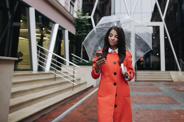 赤いコで傘雨の日と美しい若いブルネットの女性 — ストック写真