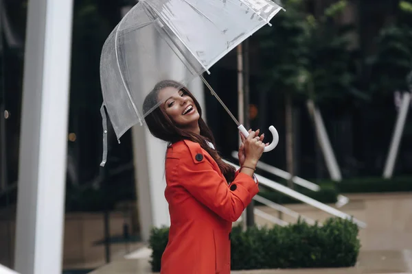 Retrato al aire libre de una hermosa joven riéndose. Chica joven caminando en la calle con paraguas . — Foto de Stock