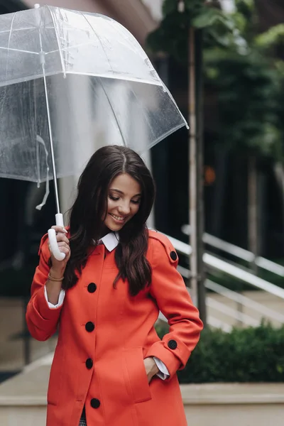 Verticale vrouw portret van jonge mooie meisje poseren op stad en hand in zak houden. Meisje staande met paraplu in straat. — Stockfoto