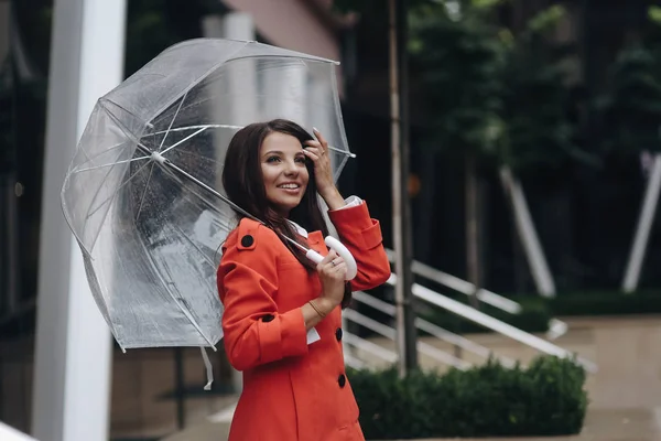 Modell poserar nära butik och fastställande hennes frisyr. Elegant flicka stående med paraply i gatan. — Stockfoto