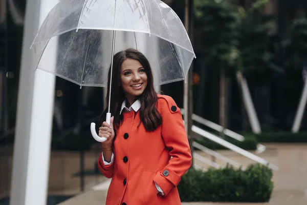 Frauenporträt eines jungen hübschen Mädchens, das in der Stadt posiert und die Hand in der Tasche hält. Mädchen steht mit Regenschirm auf Straße. — Stockfoto