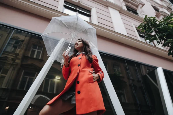 Retrato de uma menina elegante de cabelos longos com guarda-chuva dia chuvoso em casaco vermelho no fundo da cidade . — Fotografia de Stock