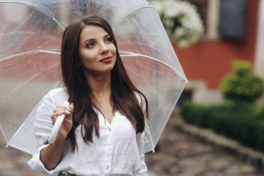 Şehir merkezinde bir yürüyüş, Genç ve şık kadın kasaba etrafında yürüyüş. Şeffaf şemsiye ile sokakta yürüyüş güzel esmer genç kadın.