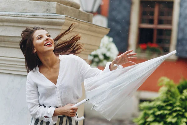 Mutlu kız, şehrin etrafında yaz aylarında sokakta yürüyor, onun şemsiye ile oynarken, sütunun yakınında ayakta.