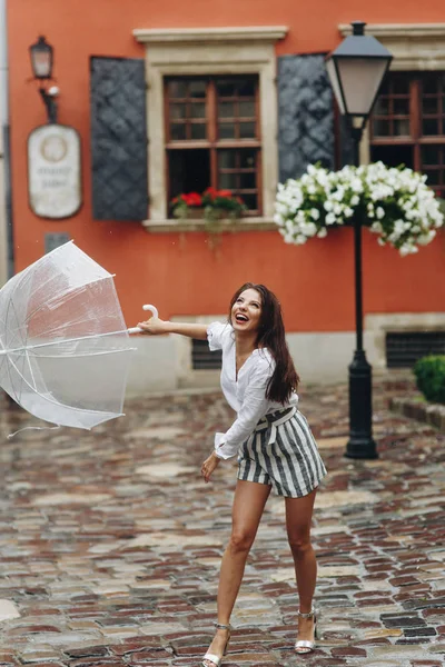 Emotioneel portret van een gelukkig en stijlvol meisje, spelen met haar paraplu. Het is zomer regen. — Stockfoto