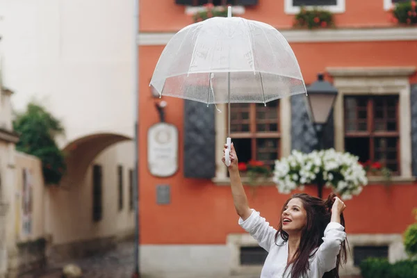 一个快乐的女孩拿着雨伞在城镇的街道上走来走去。复制空间. — 图库照片