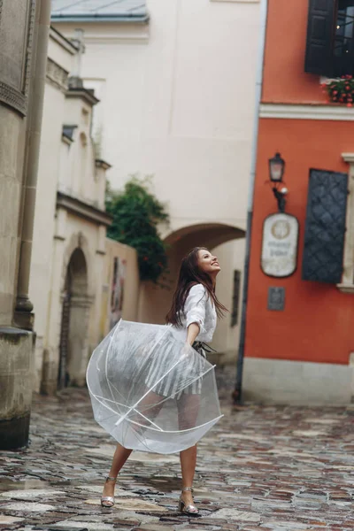 Portrait d'une fille heureuse avec parapluie près de la vieille maison jouant avec parapluie. C'est la pluie d'été . — Photo