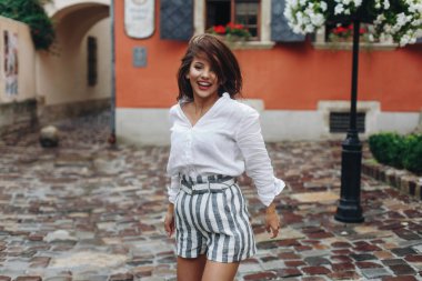 Uzun saçlı gülen genç güzel kadınların duygusal portresi, kız atlar, eski sokak arka plan.