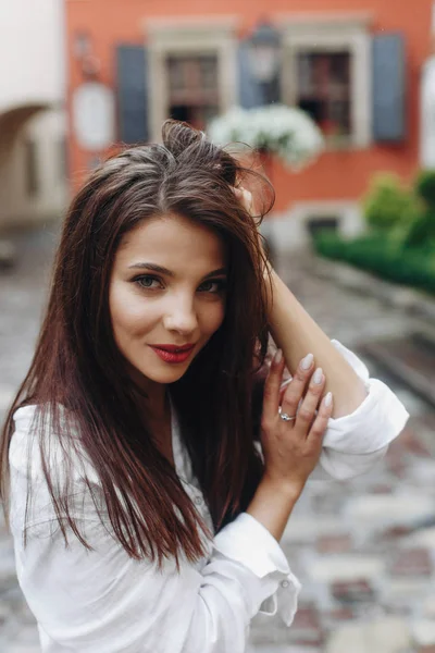 Vertical close up portrait of beautiful woman with long hair, old street background. Model looking at camera, sexy look.