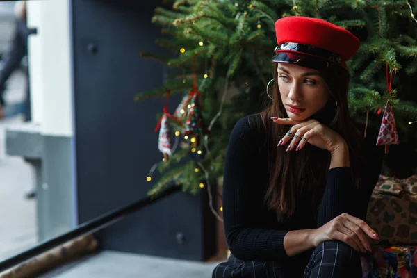 Hermosa Joven Elegante Gorra Roja Sentada Fondo Árbol Navidad Regalos —  Fotos de Stock