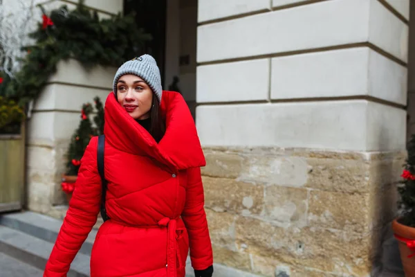 女人走在圣诞树销售处附近的大街上 复制右侧的空间 在寒冷的冬日 穿着红色冬衣的布鲁内特女人在街上散步 圣诞假期概念 — 图库照片