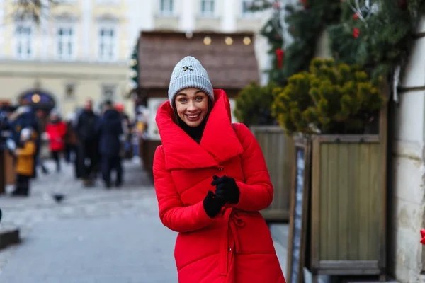 크리스마스 박람회의 배경에 쾌활한 여자의 초상화와 카메라를보고 거리에 재킷에 크리스마스 — 스톡 사진